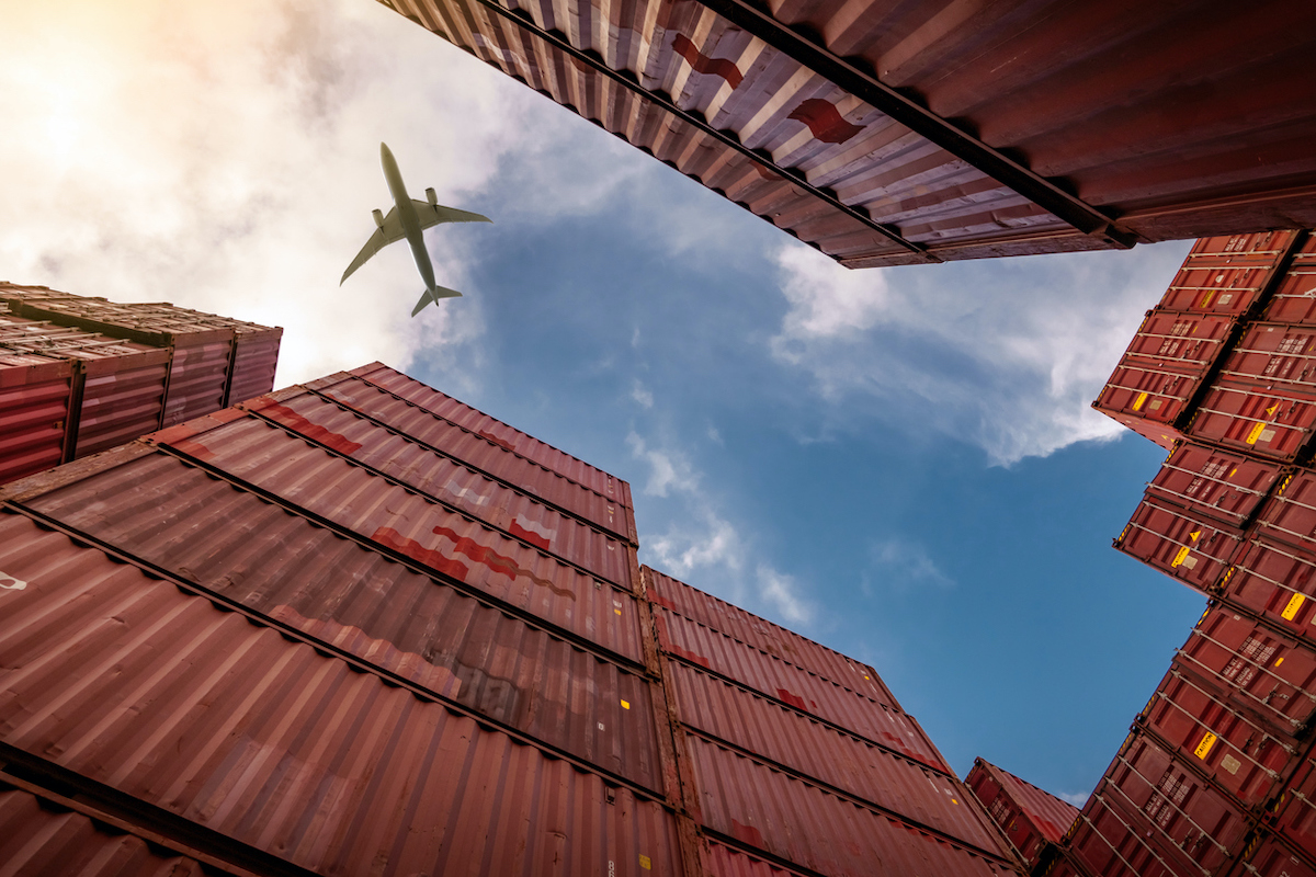 Airplane flying over shipping containers istock  fahroni  1257175043